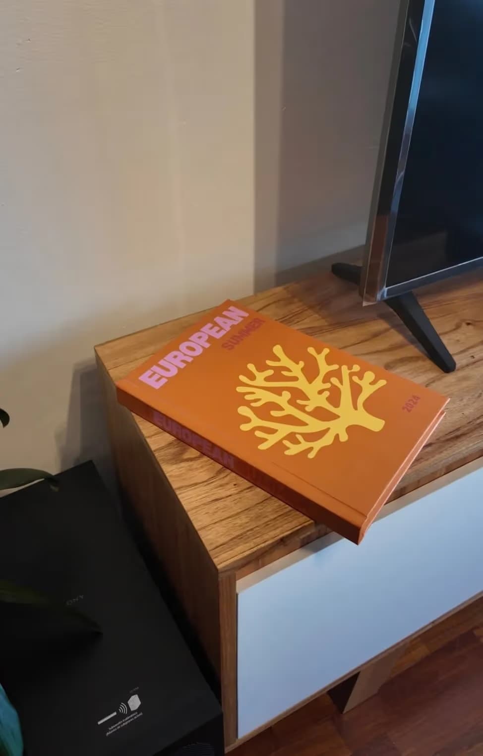 Fotolibro de hojas duras con tapa naranja apoyado sobre un mueble